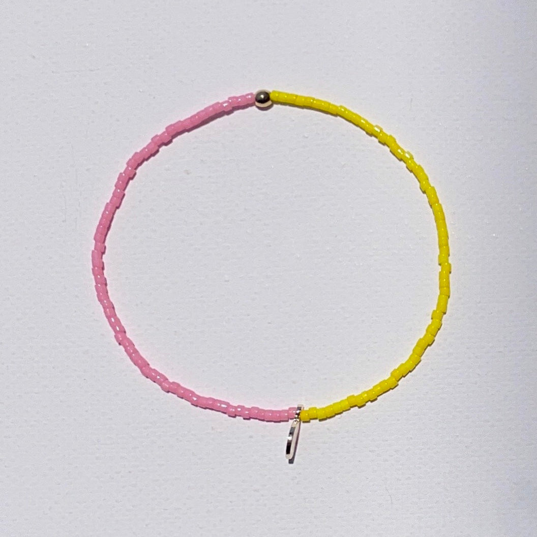 B-Color bright Yellow and Pink beaded bracelet with gold plated detail and an engraved gold tone STRIPE+BEAT plus charm