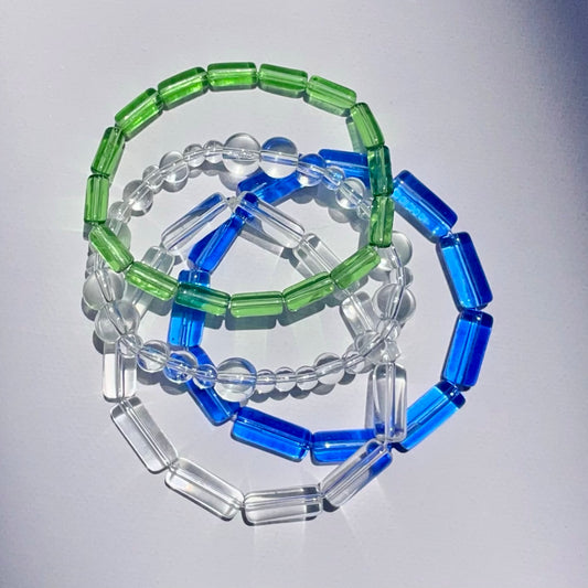Elements Bracelet collection laid flat on top of each other showing four color and style options inspired by nature