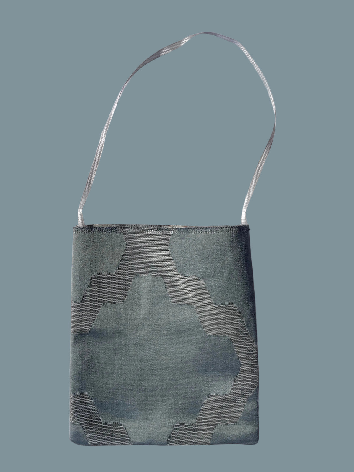 A small fabric shoulder bag with a geometric pattern in muted blue-gray and gray tones, featuring a thin matching shoulder strap.