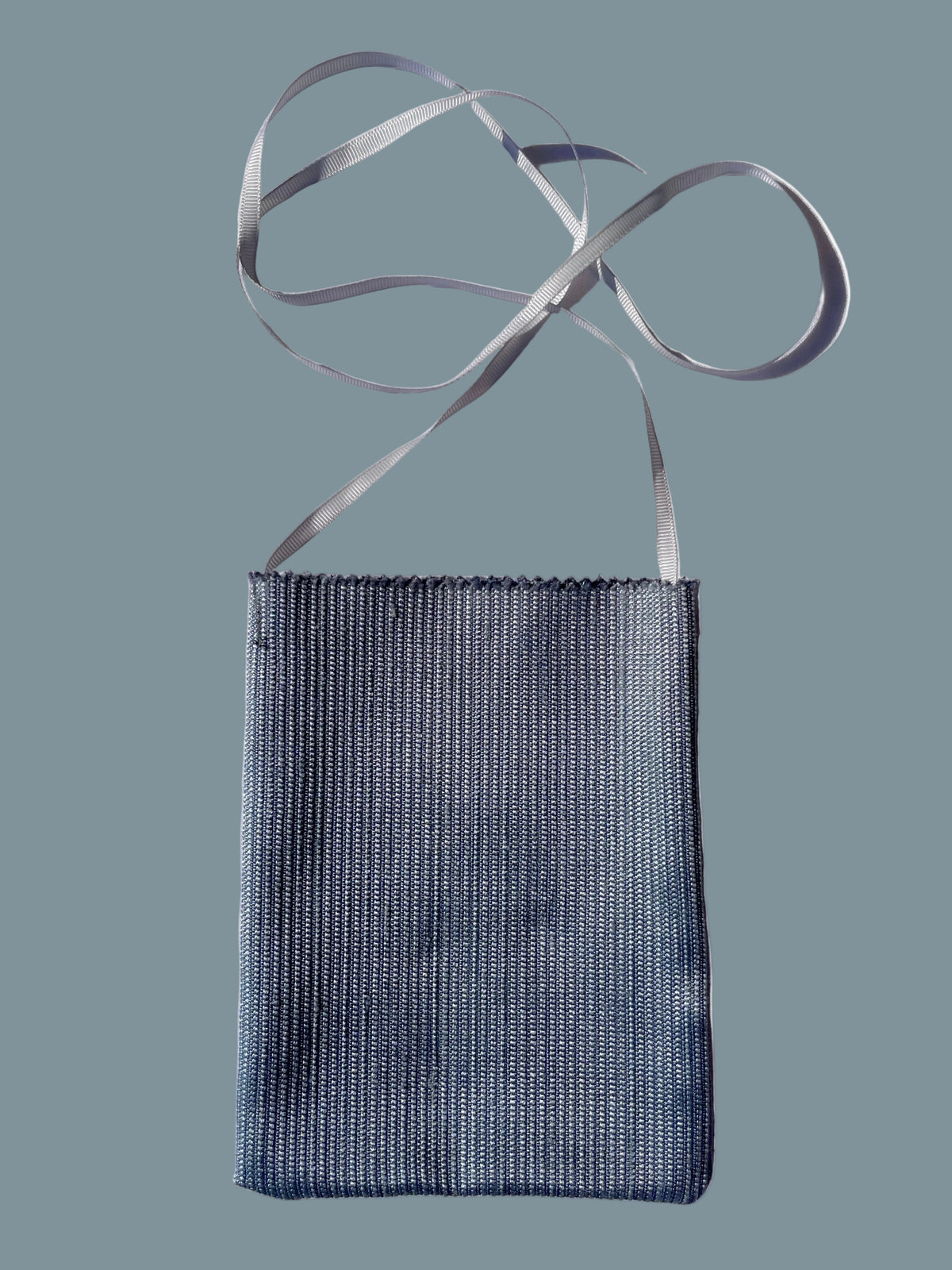 A small rectangular woven fabric pouch in a muted blue-gray color with a thin light gray strap