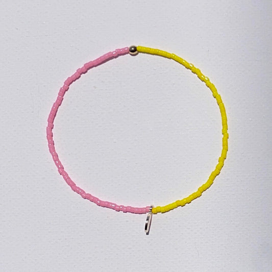 B-Color bright Yellow and Pink beaded bracelet with gold plated detail and an engraved gold tone STRIPE+BEAT plus charm