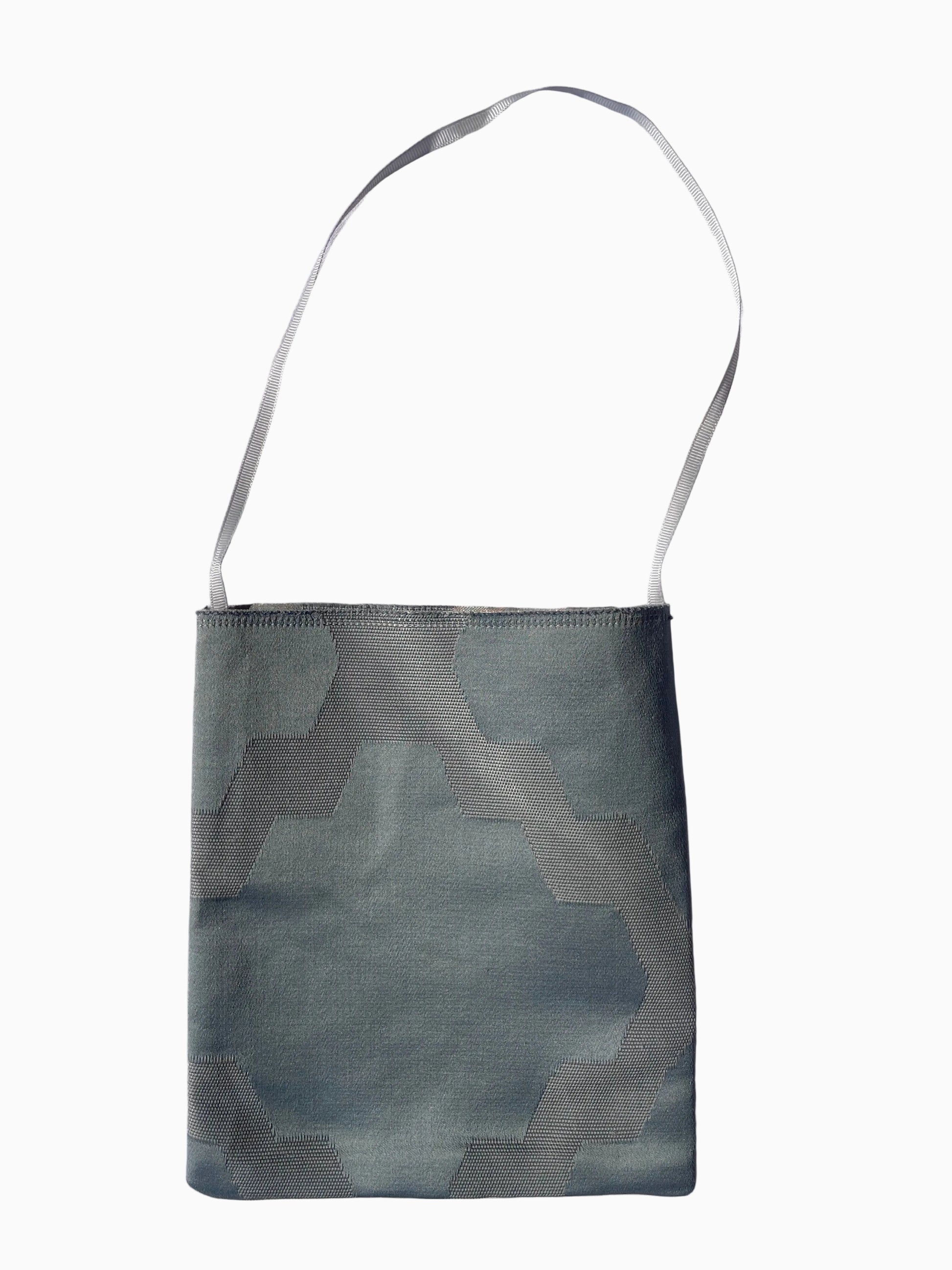 A small fabric shoulder bag with a geometric pattern in muted blue-gray and gray tones, featuring a thin matching shoulder strap.