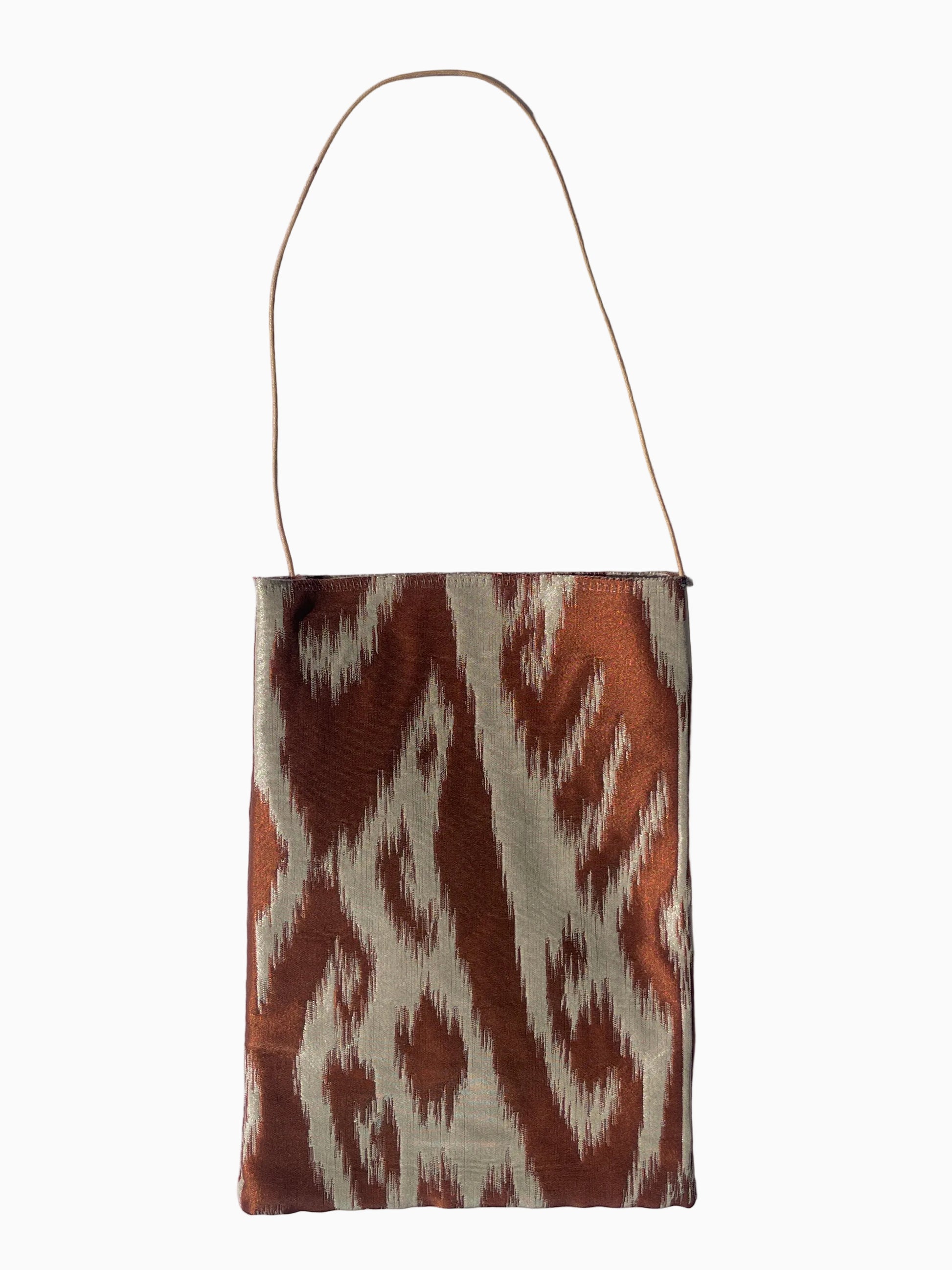 A small rectangular shoulder bag with a thin shoulder strap, featuring a brown and cream ikat pattern.