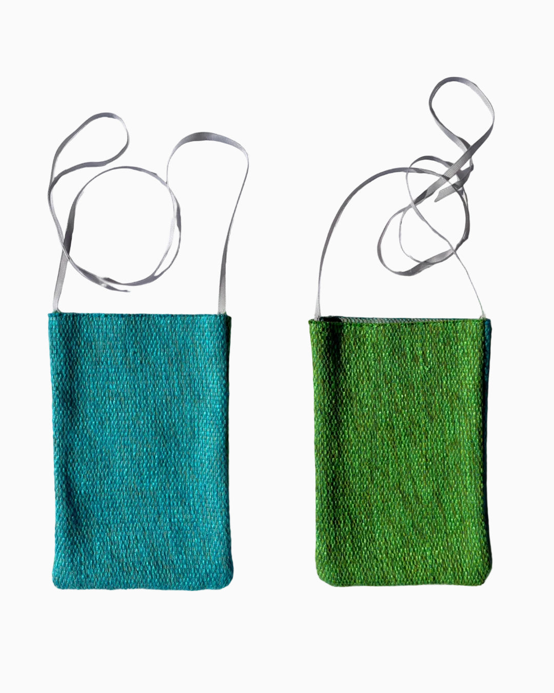 Two small woven shoulder bags shown side by side on a white fabric background, one in teal-blue and one in bright green, both with thin gray straps.
