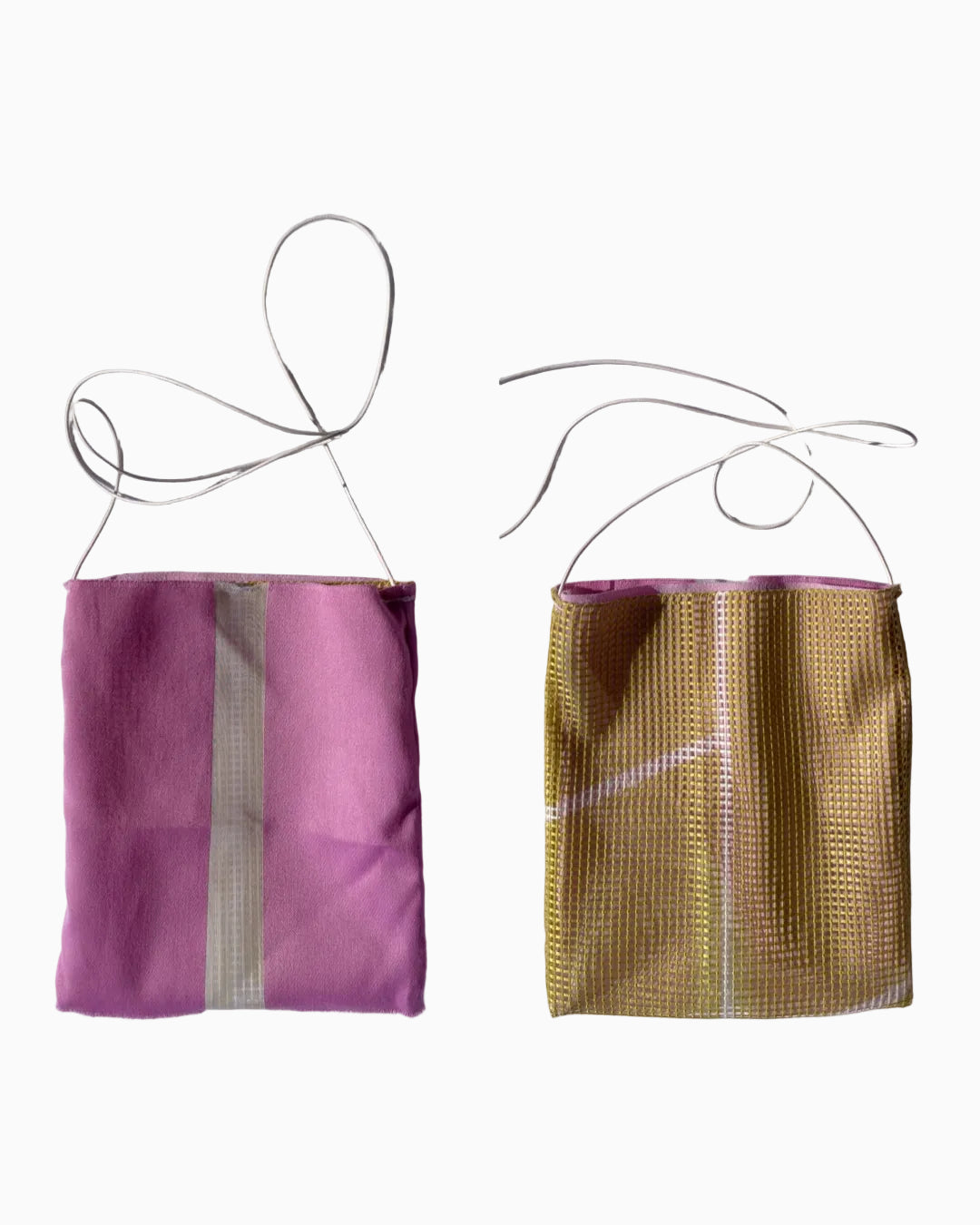 Two small mesh drawstring pouches or bags shown side by side on a wrinkled white fabric background. The left pouch is solid pink with a vertical white stripe, and the right pouch is metallic gold with a white stripe.